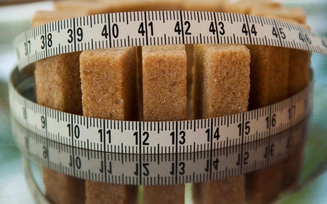 A tape measure around some sugar bars representing sugar reduction by following some guidelines for consuming less sugar.
