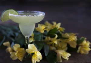 A classic margarita with flowers around it to represent alcoholic beverages that can contain a lot of artificial sugar. 