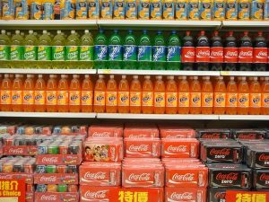 A picture of soda bottles lined up on a shelf to represent how easy it is to over-consume sugar. 