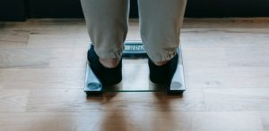 A person stepping on a scale to discuss how some people can be weight loss resistant and why that might be.