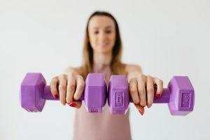 An image of a girl lifting weights to discuss exercise's role in health beyond weight loss. 