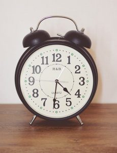 An image of a small clock sitting on a nightstand to talk about when is the best time to take naps.