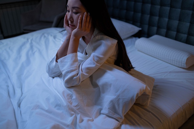 An image of a girl lying awake at night to discuss how stress can get in the way of deep sleep and getting enough sleep.