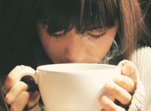 An up-close image of a person clutching a coffee cup to discuss signs a person is not getting enough sleep.