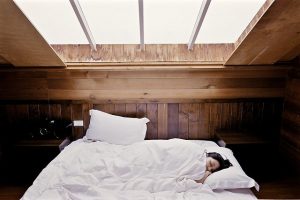 An image of a girl sleeping under white sheets with the sun coming in to discuss when needing naps is a problem.