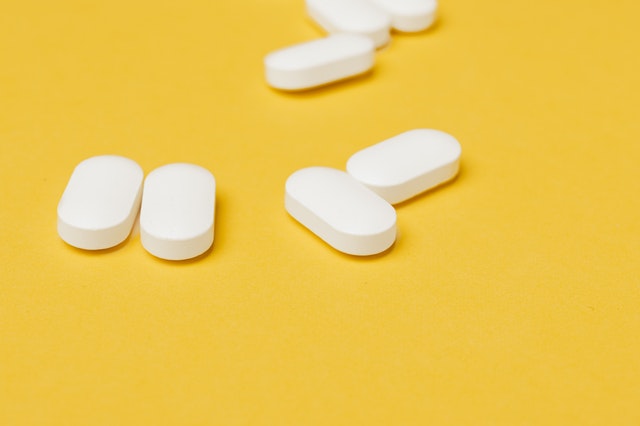 An image of white capsules against a yellow background to discuss how supplements can help with healing different health conditions.