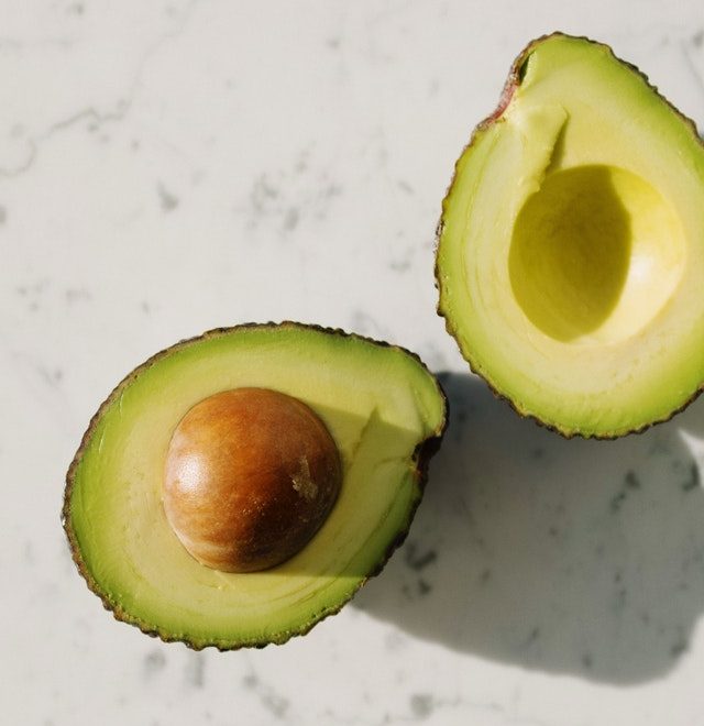 An image of an avocado cut in half to talk about its benefits as a superfood and the essential vitamins and minerals in contains.