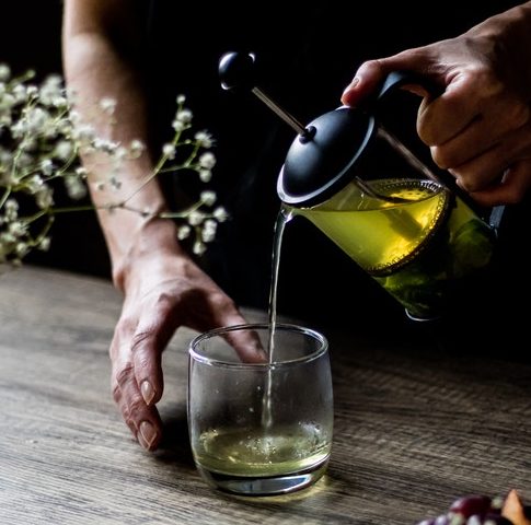 An image of a woman's hands pouring tea into a glass to talk about its benefits as a superfood and the essential vitamins and minerals in contains.