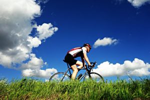 An image of a guy bicycling to talk about the benefits of cardio and HIIT training.