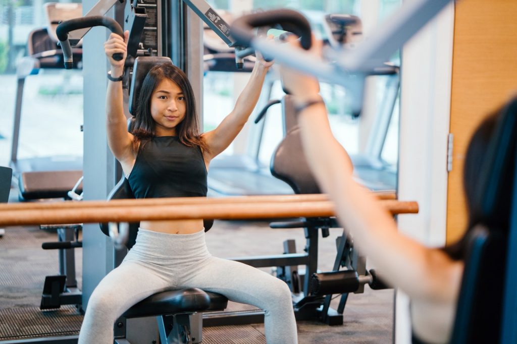 An image of a girl using a weight machine to discuss the benefits of strength training for wellness.