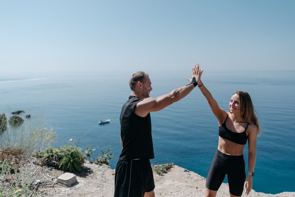 An image of a man and a woman giving each other a high-five after working out to discuss ways to make exercise fun i.e. working out with a friend. 