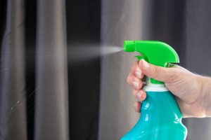 An image of someone cleaning with a spray bottle to talk about how to make your own natural cleaning products. 