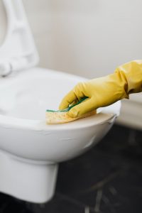 An image of a person's hand cleaning a toilet to talk about how to clean a toilet without using chemical cleaners.