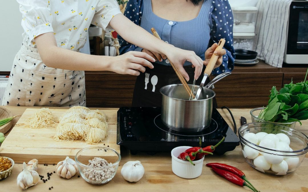 Two people cooking pasta in a pot to talk about how to choose the safest cooking utensils