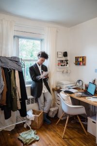 An image of a girl in a bedroom with clutter all around her to talk about how clutter can make a person lazy and affect their physical health in many ways. 