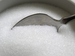 An image of a spoon dipping into sugar to talk about why a sugar-free diet or reducing your sugar intake can not only help with weight loss but your health overall. 