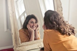 An image of a person looking into a mirror to talk about applying the Six Pillars of Eudaimonic Happiness. 